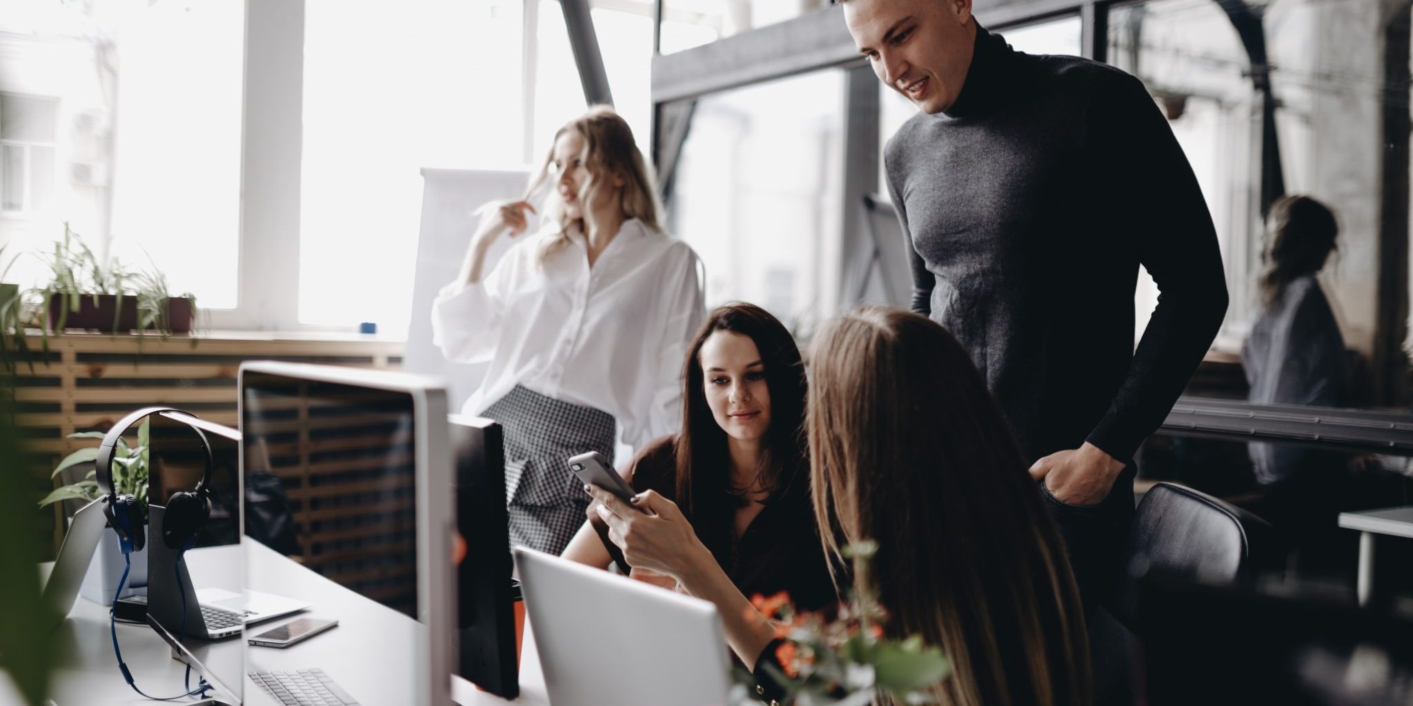 Young team works at a desks with a computer and laptops in a light modern open space office